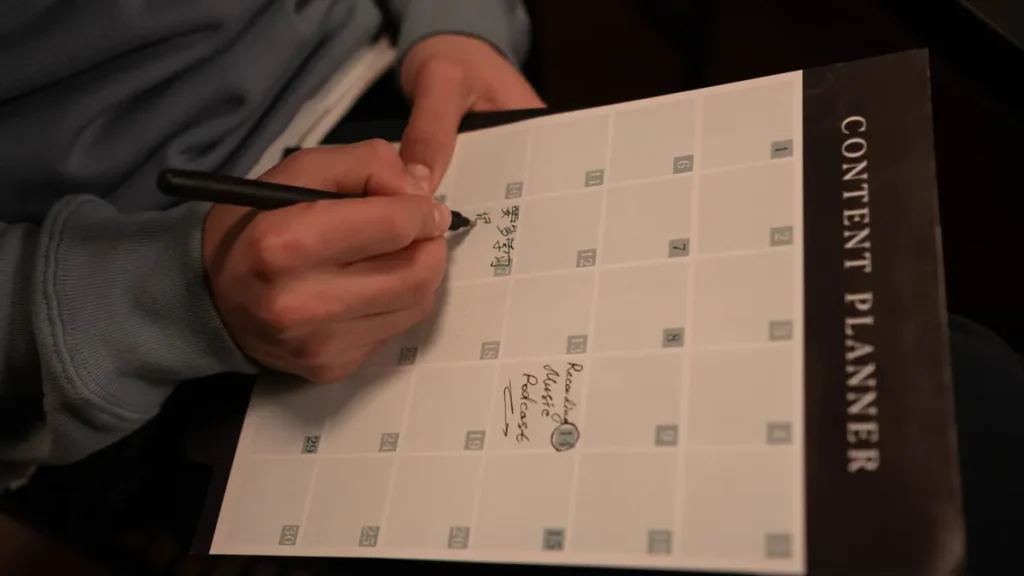 Person writing in a content planner notebook