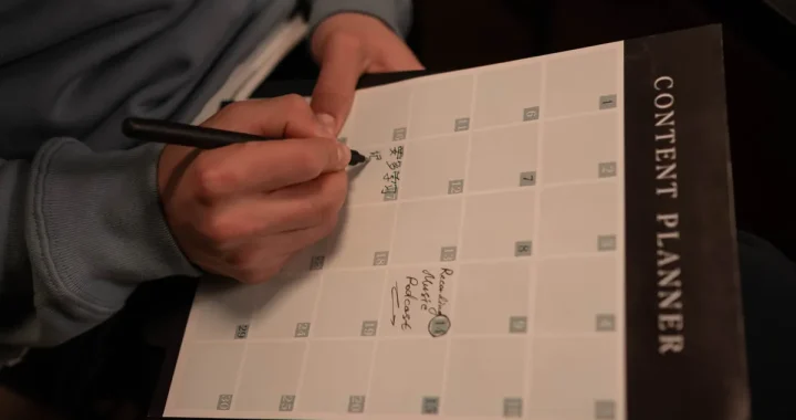 Person writing in a content planner notebook