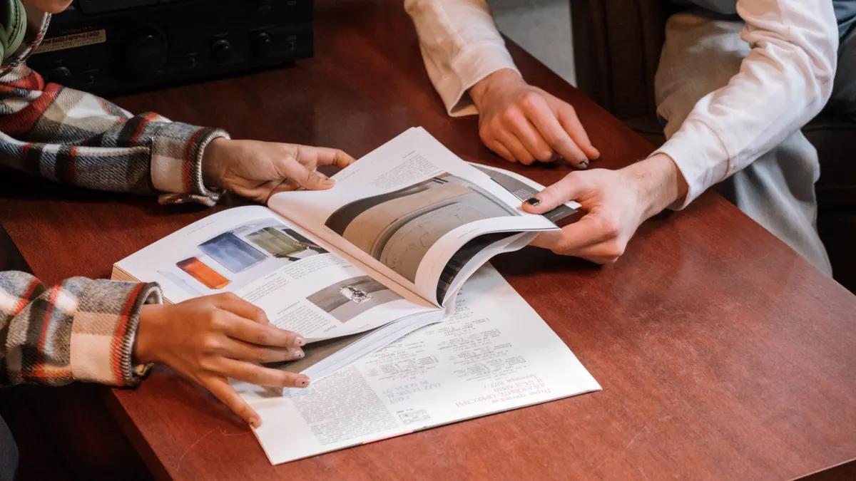 Two people reviewing a magazine spread at a table